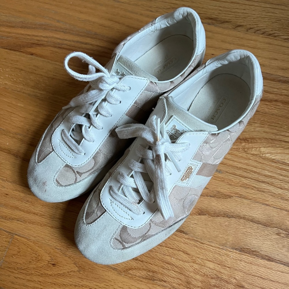 White and beige coach sneakers with coach logo detail on sides.